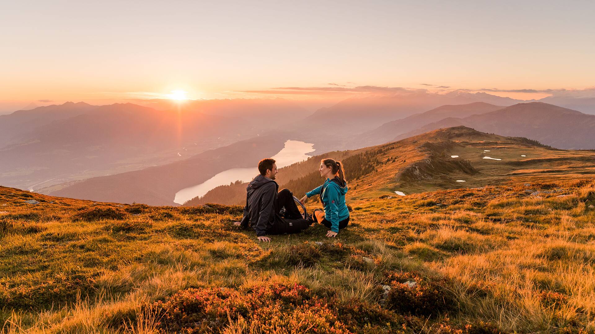 Frau und Mann genießen den Sonnenaufgang im Herbst am Mirnock